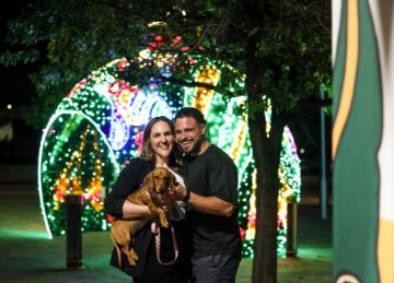 Image of couple and a dog visiting the Christmas lights.